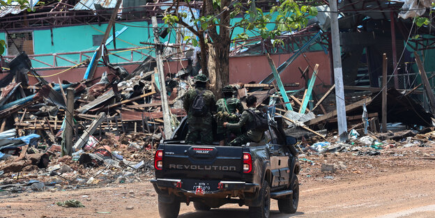 KNLA-Rebellen fahren fahren am 15. April in einem Pickup an einem Haus in Myawaddy vorbei , das durch einen Luftangriff des Militärs zertört wurde