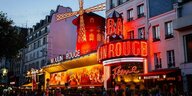 Das Moulin-Rouge-Theater erleuchtet inmitten einer Häuserreihe in einer belebten Straße